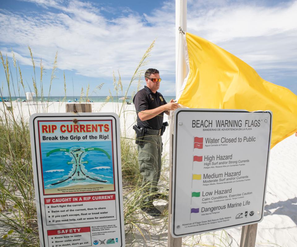 Sgt. Mike Morris, with the Bay County Sheriff’s Office, hangs a yellow beach warning flag on Thursday. Green flags are no longer used by the department.