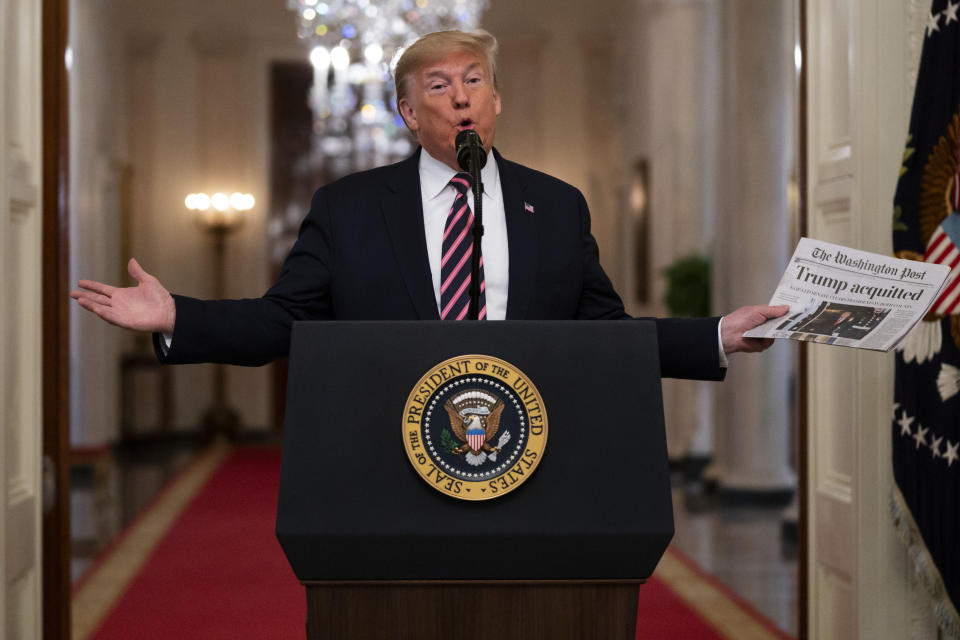 President Donald Trump holds up a newspaper with a headline that reads "Trump acquitted" as he speaks in the East Room of the White House, Thursday, Feb. 6, 2020, in Washington. (AP Photo/Evan Vucci)