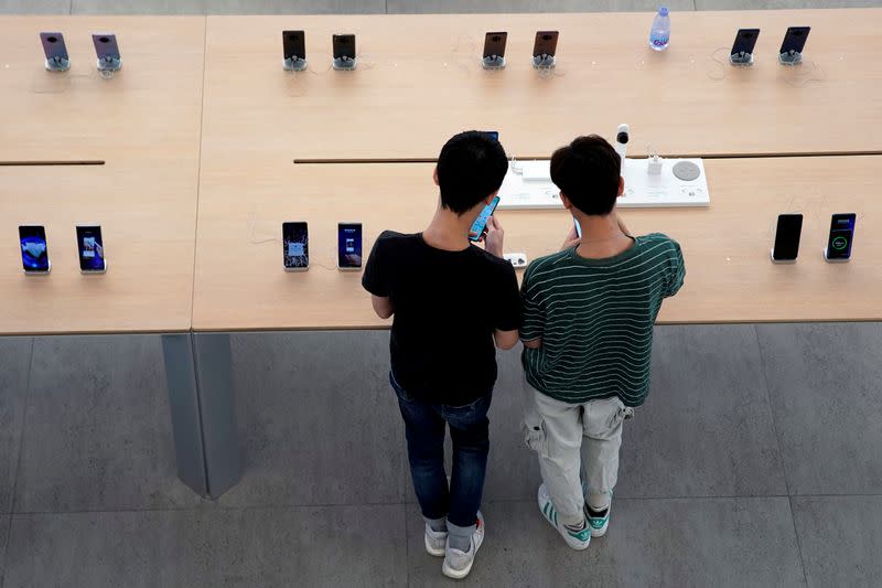 FILE PHOTO: People look at smartphones in Huawei's first global flagship store in Shenzhen