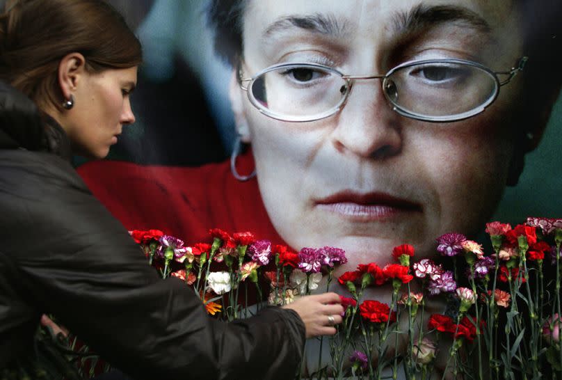 In this Oct. 7, 2009 file photo, a woman places flowers before a portrait of slain Russian journalist Anna Politkovskaya, in Moscow.