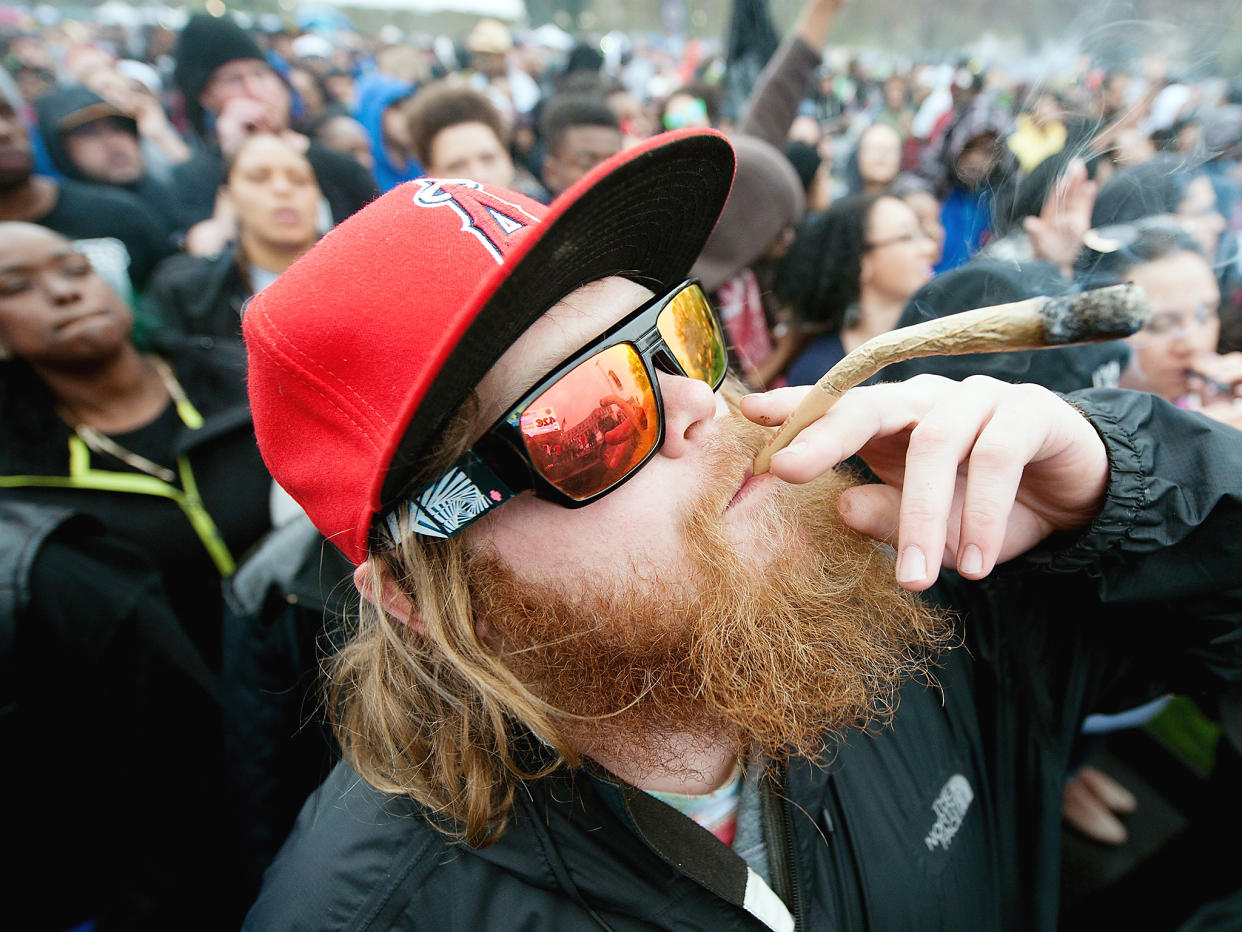 Nic Ruhl takes a pull on a giant hand rolled joint at precisely 4:20pm MDT during the Denver 420 Rally at Civic Center Park in Denver, Colorado: Getty Images