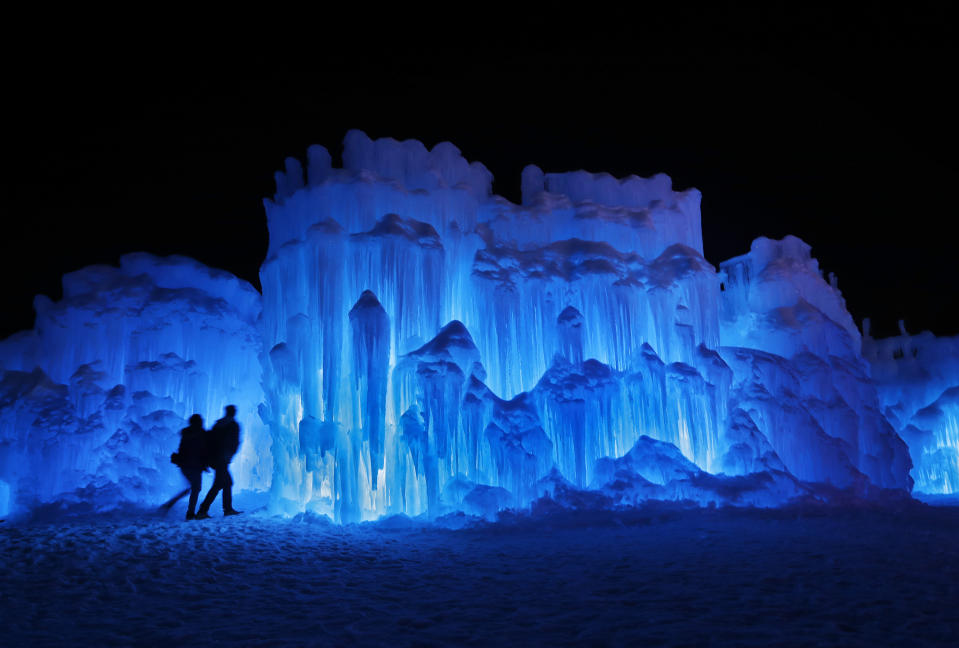 A couple heads towards an entrance to a cavern at Ice Castles in North Woodstock, N.H. A team starts building massive walls in December to create a spectacular winter experience. (Photo: Robert F. Bukaty/AP)