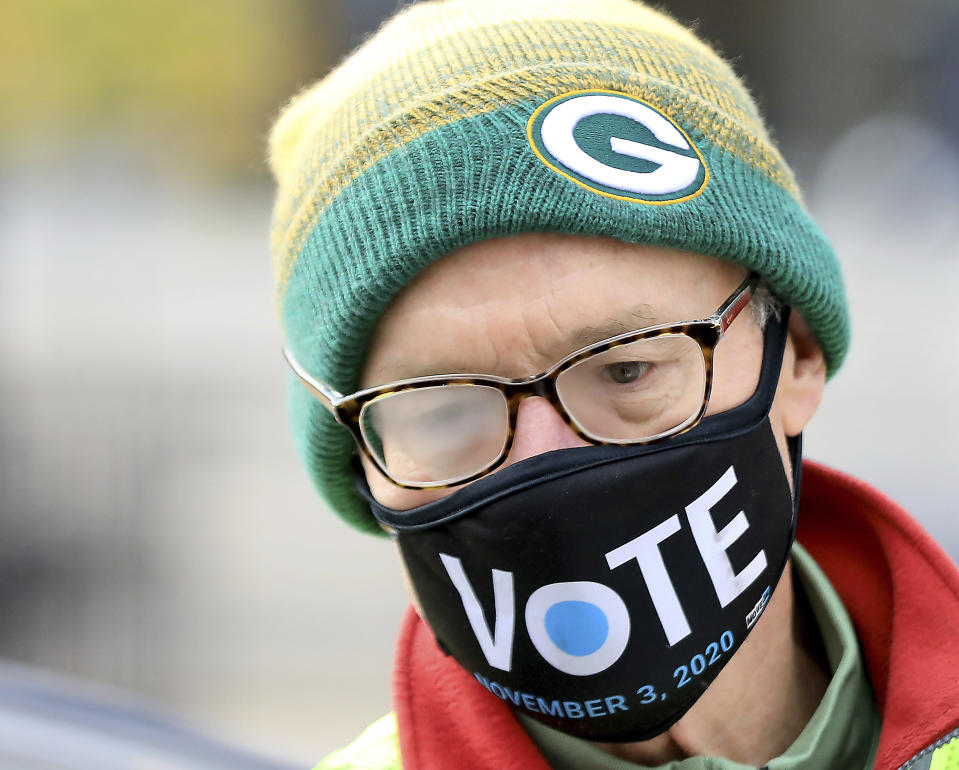 Madison, Wis. poll worker Wade DallaGrana assists a voter with their ballot while tending to a drive-up balloting station outside City-County Building Tuesday, Oct. 20, 2020, in Madison, Wis. (John Hart/Wisconsin State Journal via AP)