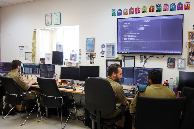 Technologists with the Israeli military's Matzpen operational data and applications unit confer at their stations at an IDF base in Ramat Gan