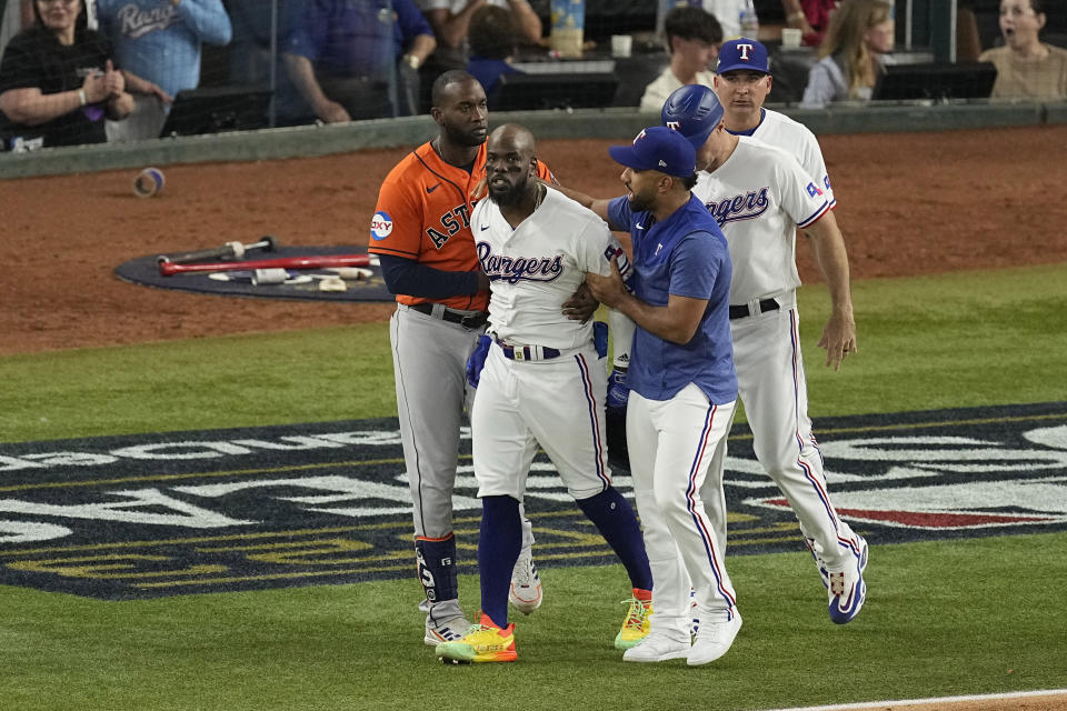 Texas Rangers' Adolis Garcia is restrained after being hit by a pitch during the eighth inning in Game 5 of the baseball American League Championship Series against the Houston Astros Friday, Oct. 20, 2023, in Arlington, Texas. (AP Photo/Tony Gutierrez)