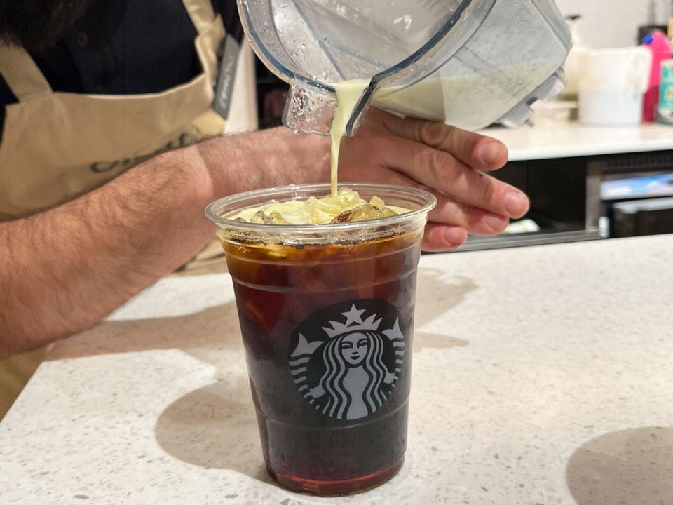 barista pouring foam ontop of starbucks drink