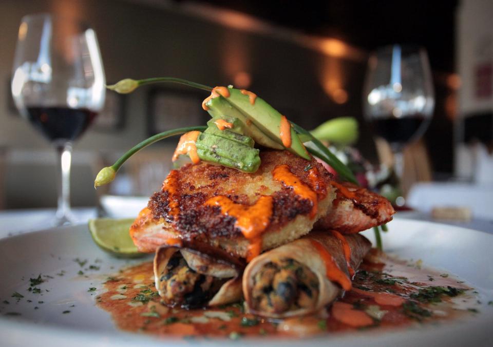 Paramount Grill's Southwestern salmon over black bean, sweet potato and white cheddar cheese enchiladas, with fried green tomato, avocado, chili-citrus vinaigrette and chipotle aioli.