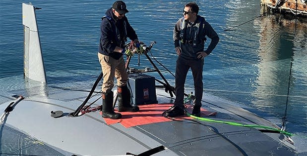 DARPA program manager Dr. Kyle Woerner (right) talks with a Northrop Grumman team member while standing atop the Manta Ray vehicle.