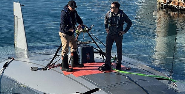 DARPA program manager Dr. Kyle Woerner (right) talks with a member of the Northrop Grumman team while standing atop the Manta Ray vehicle.