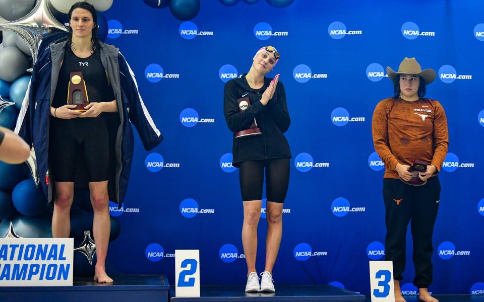 Lia Thomas, left, accepts the winning trophy alongside second place finisher Emma Weyant, centre, and third place finisher Erica Sullivan, right - Rich von Biberstein/Icon Sportswire via Getty Images