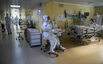 A medic wearing a special suit to protect against coronavirus sits near a patient with coronavirus at an ICU at the Moscow City Clinical Hospital 52, in Moscow, Russia, Tuesday, Oct. 19, 2021. Russia hit another daily record of coronavirus deaths Tuesday as rapidly surging infection rates raised pressure on the country's health care system and prompted the government to suggest declaring a nonworking week.(AP Photo/Alexander Zemlianichenko)