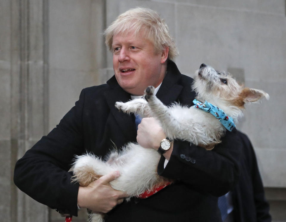 Britain's Prime Minister and Conservative Party leader Boris Johnson holds his dog Dilyn as he leaves after voting in the general election at Methodist Central Hall, Westminster, London, Thursday, Dec. 12, 2019. The general election in Britain on Thursday will bring a new Parliament to power and may lead to a change at the top if Prime Minister Boris Johnson's Conservative Party doesn't fare well with voters. Johnson called the early election in hopes of gaining lawmakers to support his Brexit policy. (AP Photo/Frank Augstein)