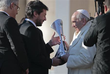 A member of Argentine soccer team San Lorenzo presents Pope Francis (R) with the replica of the trophy that they won in the Argentine soccer championship, during the Wednesday general audience in Saint Peter's square at the Vatican December 18, 2013. REUTERS/Tony Gentile