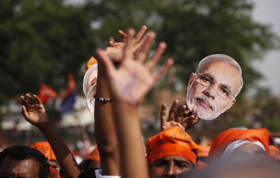 FILE - In this May 8, 2014 file photo, a supporter of India’s main opposition and Hindu nationalist Bharatiya Janata Party (BJP) holds up a mask of their prime ministerial candidate Narendra Modi in Varanasi, in the northern Indian state of Uttar Pradesh. Indian elections results due Friday, May 16, 2014, provide a chance to repair relations with the U.S. that were strained by the arrest of an Indian diplomat in New York. But there's a big catch: Washington's uneasy relationship with the man expected to become India's next prime minister. Hindu nationalist leader Modi was in 2005 denied a U.S. visa for alleged complicity in religious riots in 2002 that killed more than 1,000 Muslims. Exit polls show his Bharatiya Janata Party and its allies with a large lead over the ruling Congress party and its allies after voting ended Monday, May 12. (AP Photo/ Rajesh Kumar Singh, File)