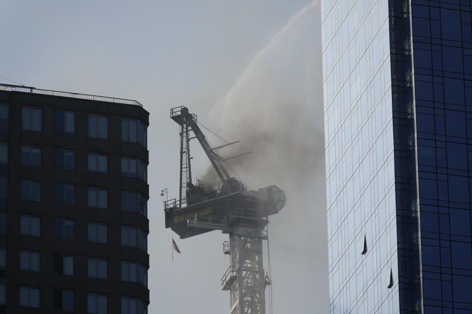 Smoke rises from a construction crane that caught fire in Manhattan, Wednesday, July 26, 2023, in New York. The crane lost its long arm, which smashed against a nearby building, dangled and then plummeted to the street as people ran for their lives on the sidewalk below. Some people suffered minor injuries, but no one died, according to Mayor Eric Adams .(AP Photo/Seth Wenig)