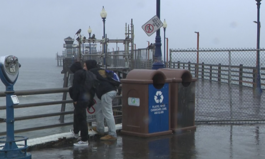 Two people stand near gates blocking off the Oceanside Pier on Aug. 20, 2023. (KSWB/FOX 5)