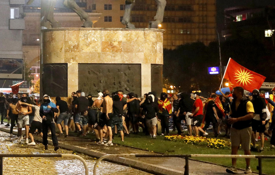 People throw stones at the parliament building in Skopje, North Macedonia, during a protest late Tuesday, July 5, 2022. Violent protests erupted in North Macedonia's capital, Skopje, where demonstrators tried to storm government buildings, after French President Emmanuel Macron last week announced the proposal, which many in the small Balkan country find controversial. (AP Photo/Boris Grdanoski)