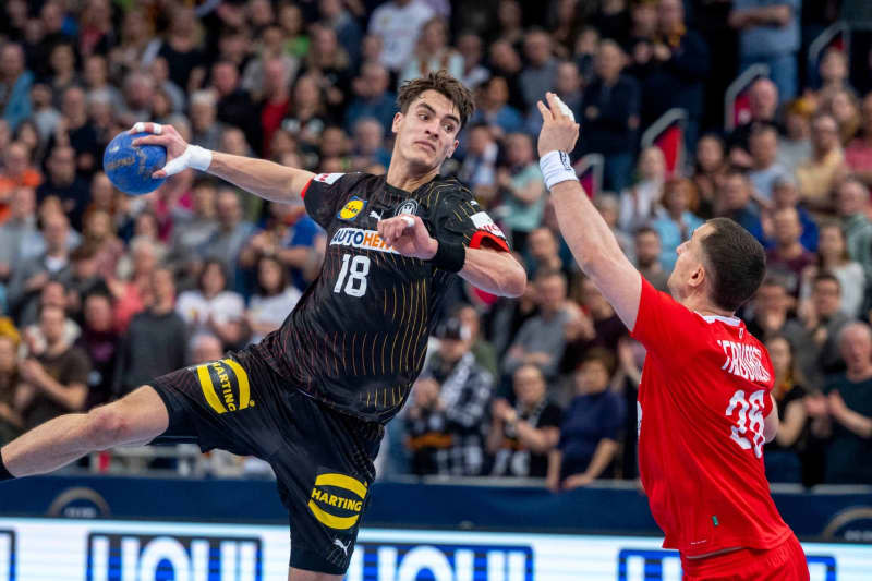Germany's Julian Koester (L) and Austria's Lukas Herburger fight for the ball during the Olympic qualification Handball match between Austria and Germany. David Inderlied/dpa