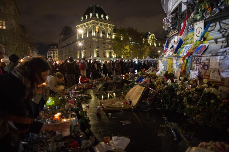 People light candles at a makeshift memorial in front of "