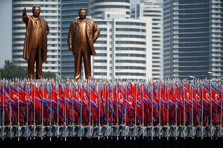 FILE PHOTO: People carry flags in front of statues of North Korea founder Kim Il Sung (L) and late leader Kim Jong Il during a military parade marking the 105th birth anniversary Kim Il Sung, in Pyongyang April 15, 2017. REUTERS/Damir Sagolj