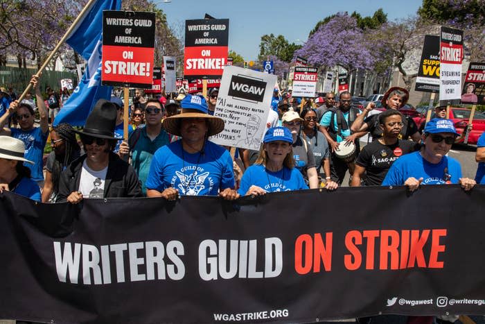 People protesting and holding a banner that says "Writers Guild On Strike"