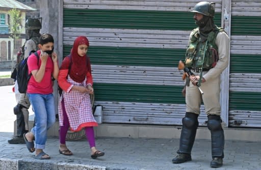 Kashmiri students walks past Indian paramilitary troopers in Srinagar during a general strike