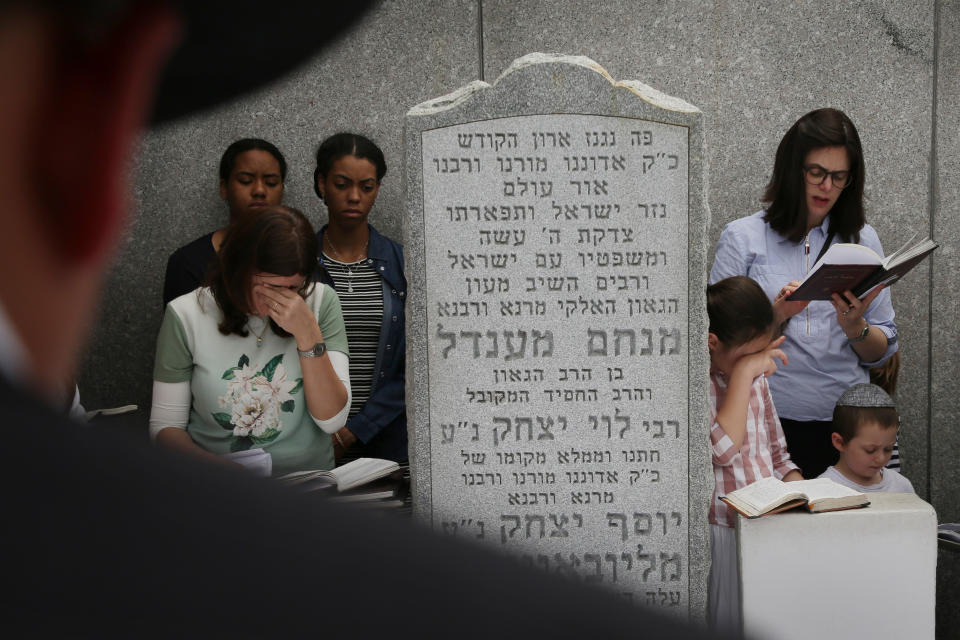 In this July 2, 2019 photo, people pray at the gravesite of Rabbi Menachem M. Schneerson in the Queens borough of New York. Men and women, young and old, make their way from around the city, the country and the world to this unassuming site, the burial place of Rabbi Menachem Mendel Schneerson, to pay their respects to the life and teachings of the revered Jewish leader of the Chabad-Lubavitch movement who died twenty-five years ago in June 1994. (AP Photo/Seth Wenig)