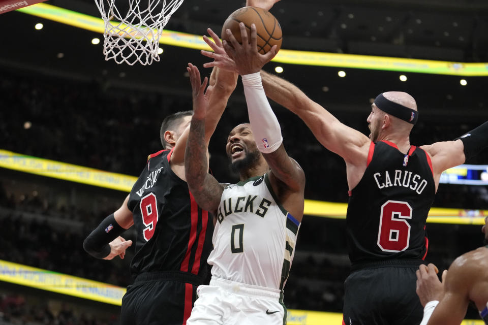 Milwaukee Bucks' Damian Lillard drives to the basket under pressure from Chicago Bulls' Nikola Vucevic and Alex Caruso during an overtime period of an NBA basketball game, Thursday, Nov. 30, 2023, in Chicago. (AP Photo/Charles Rex Arbogast)