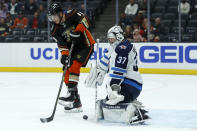 Winnipeg Jets goaltender Connor Hellebuyck, right, stops a shot by Anaheim Ducks center Troy Terry, left, during the second period of an NHL hockey game in Anaheim, Calif., Tuesday, Oct. 26, 2021. (AP Photo/Alex Gallardo)