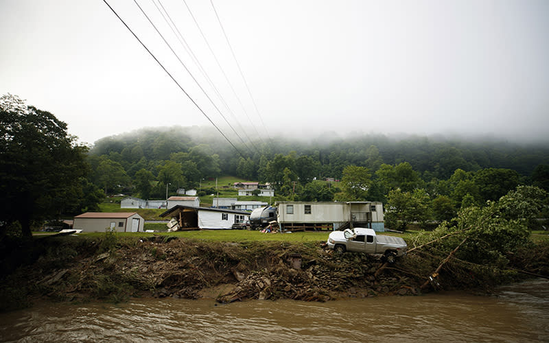 A truck sits on the edge over a river