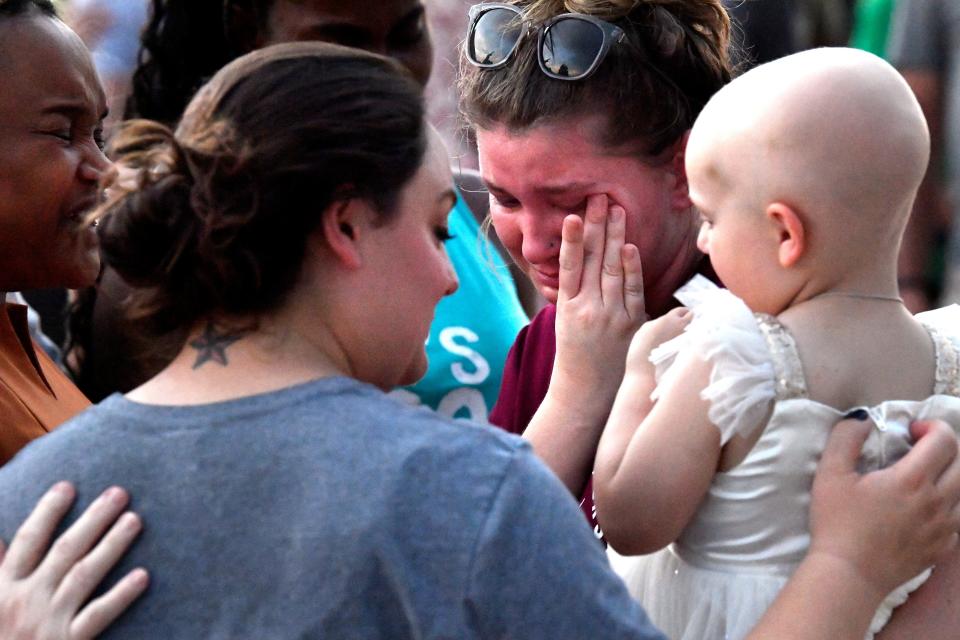 Britany Fullerton wipes at her tears as she holds Sienna Molina during an impromptu group prayer with her mother Danielle (center) and others Tuesday.