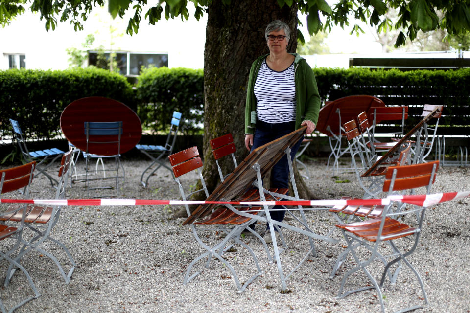 In this photo taken Friday, May 1, 2020 brewery daughter Sabine Detter stands behind barrier tape in the closed beer garden in her 120 year old family brewery and traditional Bavarian restaurant in Altoetting, Germany. The 'Graminger Weissbraeu' brewery, which has been in the same family for a century, is preparing to welcome guests back to its restaurant for the first time in two months — with new rules and fears for the future. (AP Photo/Matthias Schrader)