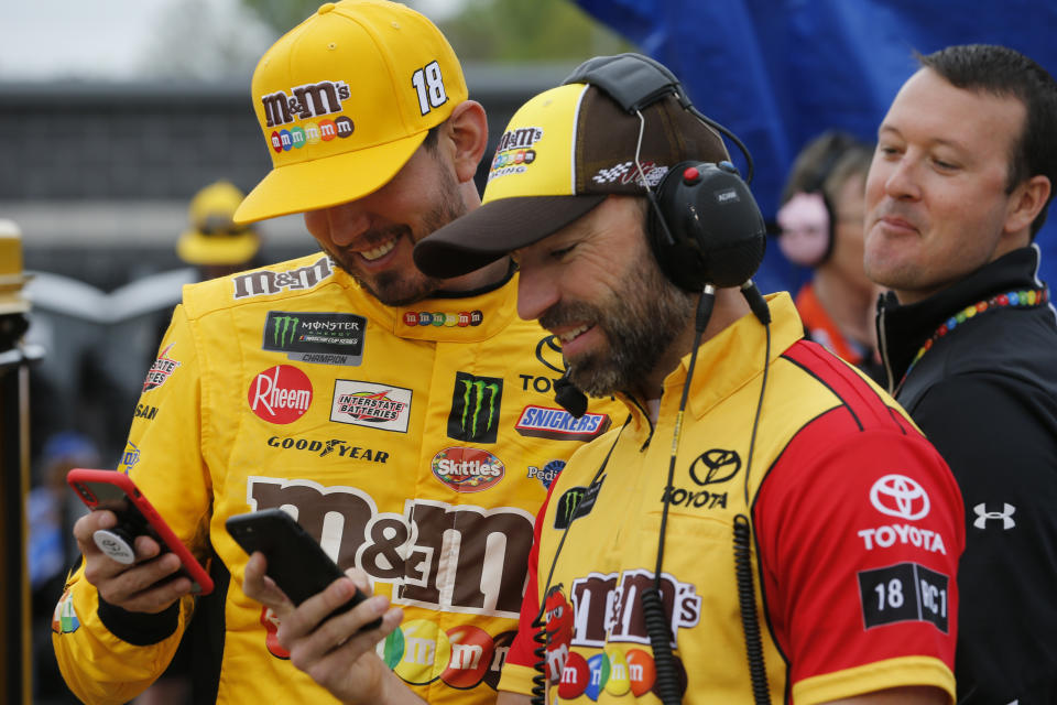 Kyle Busch, left, and his crew chief, Adam Stevens, laugh on their phones prior to qualifying for Saturday's NASCAR Cup auto race at Richmond International Raceway in Richmond, Va., Friday, April 12, 2019. (AP Photo/Steve Helber)