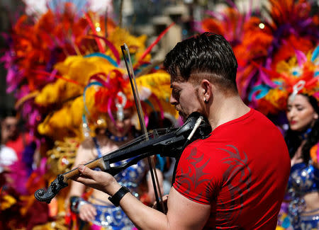 A musician plays the violin as cheerleaders dance during Labour Party celebrations at a May Day rally, after Prime Minister Joseph Muscat urged supporters to attend as a response to the revelations made by the Daphne Project, according to local media, in Valletta, Malta May 1, 2018. REUTERS/Darrin Zammit Lupi