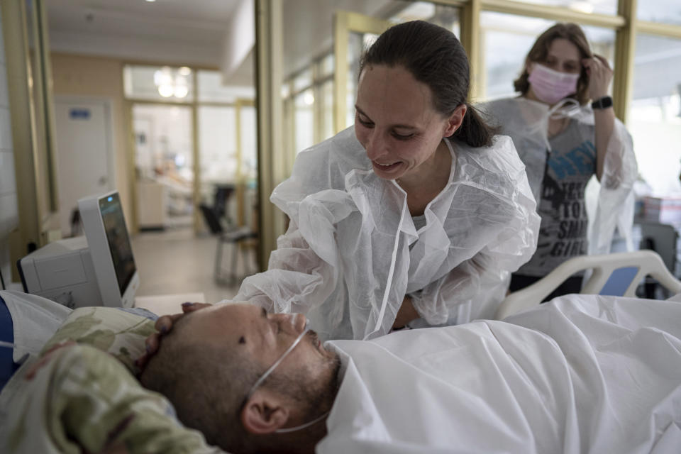 Olena smiles at her husband Maksym, an injured Ukrainian serviceman, inside the ICU of Mechnikov Hospital in Dnipro, Ukraine, Saturday, July 15, 2023. A surge of wounded soldiers has coincided with the major counteroffensive Ukraine launched last month to try to recapture its land from Russian forces. Surgeons at Mechnikov Hospital, one of the country's biggest, are busier now than perhaps at any other time since Russia began its invasion 17 months ago. (AP Photo/Evgeniy Maloletka)