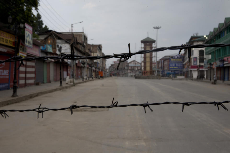 In this Tuesday, Aug. 6, 2019 photo, a deserted street is seen through a barbwire set up as blockade during curfew in Srinagar, Indian controlled Kashmir, Wednesday, Aug. 7, 2019. Authorities in Hindu-majority India clamped a complete shutdown on Kashmir as they scrapped the Muslim-majority state's special status, including exclusive hereditary rights and a separate constitution, and divided it into two territories. (AP Photo/Dar Yasin)