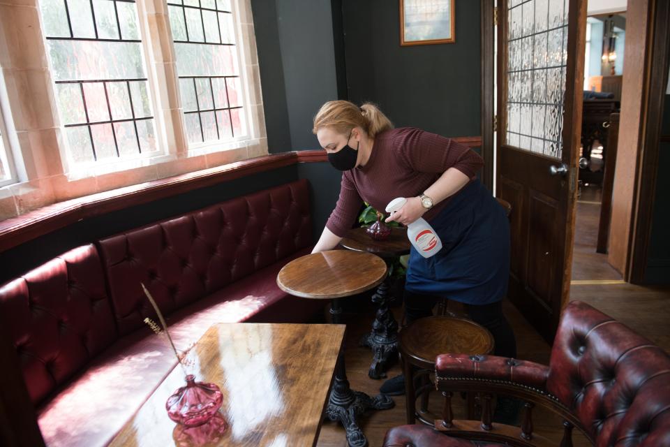 <p>Member of staff cleans table</p> (PA Wire)