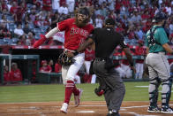 Los Angeles Angels' Brandon Marsh, left, collides with home plate umpire Alan Porter, center, as he scores on a triple by Shohei Ohtani while Seattle Mariners catcher Cal Raleigh stands at the plate during the first inning of a baseball game Saturday, Sept. 25, 2021, in Anaheim, Calif. (AP Photo/Mark J. Terrill)