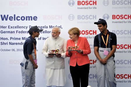 German Chancellor Merkel interacts with an employee as India's PM Modi and another employee look on at the Bosch Vocational Center in Bengaluru