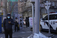 A police vehicle and security guards monitor the entrance to the Anzhen residential community in Beijing, China, Tuesday, Jan. 25, 2022. Beijing residents are coping with strict local lockdowns and COVID-19 testing requirements as the Chinese capital seeks to prevent a major coronavirus outbreak ahead of the opening of the Winter Olympics in less than two weeks. (AP Photo/Ng Han Guan)