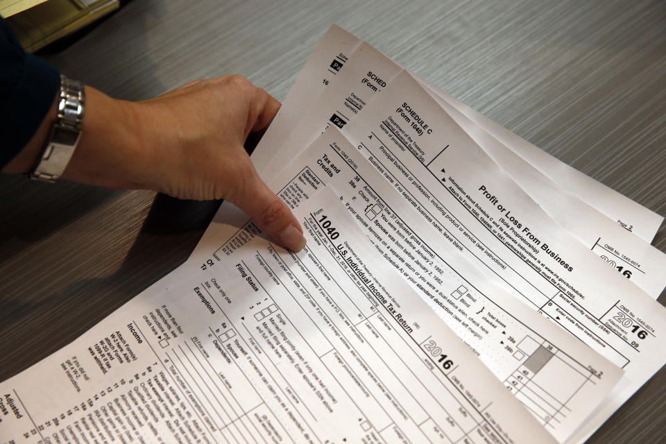 FILE - In this Jan. 14, 2017, file photo, tax preparation firm owner Alicia Utley reaches for hard copies of tax forms in her offices at Infinite Tax Solutions, in Boulder, Colo. If your tax refund vanishes too quickly, don’t have it all sent directly to your checking account. The IRS can divvy your refund among up to three different accounts, including IRAs, college savings accounts and brokerage accounts. (AP Photo/Brennan Linsley, File)