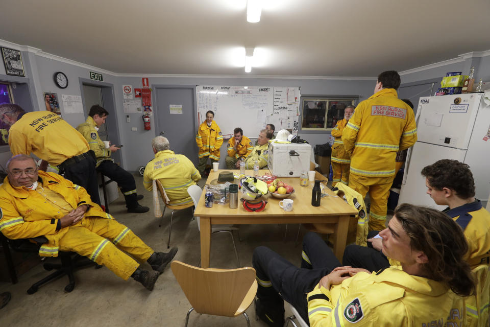 In this Jan. 10, 2020, photo, firefighters and army personnel gather in a common room at the Rural Fire Service fire house at Burragate, Australia. It seemed imminent to those hunkering at the fire station that "The Beast" would finally roar through. But on this night the wildfire only crept closer, prodding forward a few tentative fingers before going dormant again as the winds died. (AP Photo/Rick Rycroft)