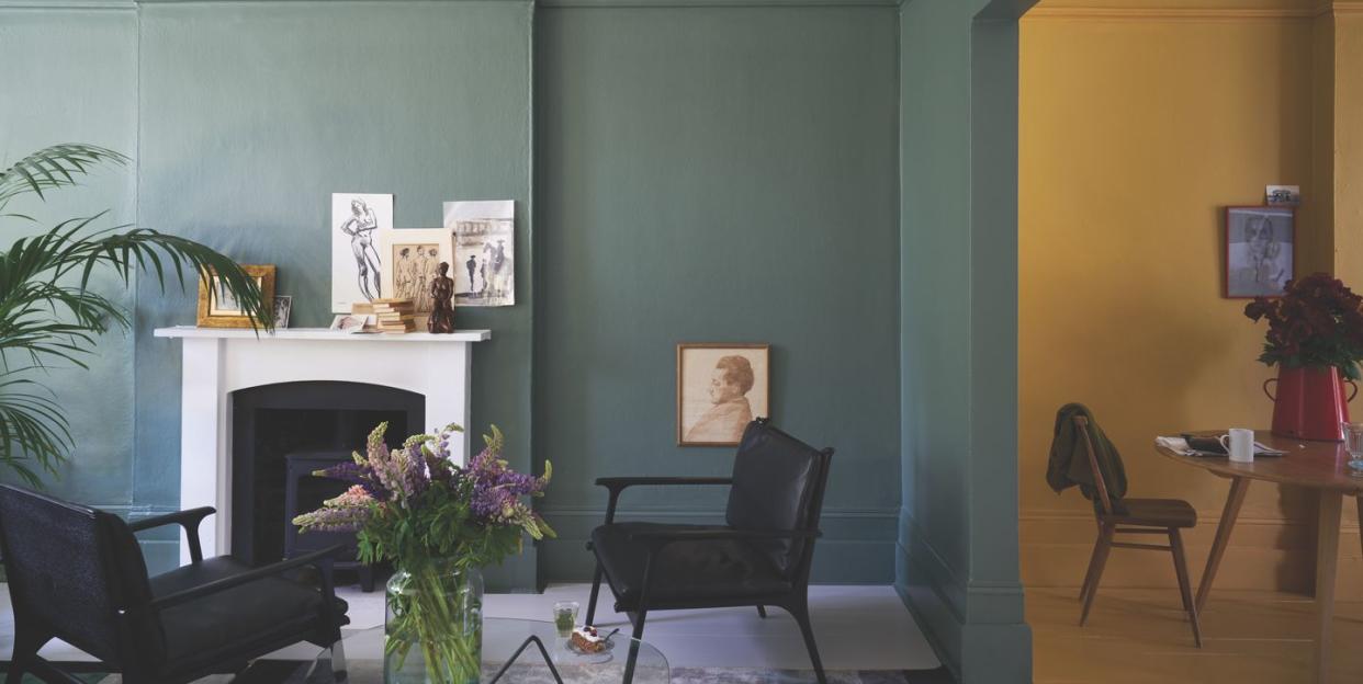 a room painted in green and yellow farrow ball paint with fireplace and armchairs