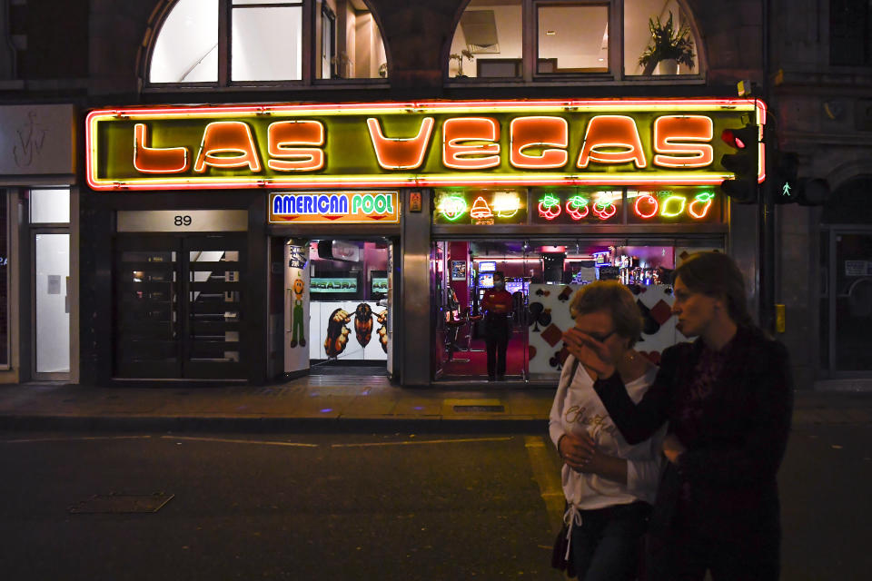 People walk past a casino in Soho, in London, Tuesday, Sept. 22, 2020. Britain's Prime Minister, Boris Johnson, has announced that pubs and restaurants closing at 10pm, due to the spike of cases of coronavirus across the United Kingdom. (AP Photo/Alberto Pezzali)