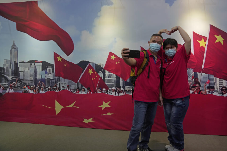 A couple pose in front of a banner featuring Chinese flags at an exhibition to mark the 25th anniversary of the former British colony's return to Chinese rule, in Hong Kong, Friday, June 24, 2022. Many in Hong Kong worry that communist-ruled China is exerting ever more control over semi-autonomous Hong Kong. Critics of Beijing's policies say it is contrary to its promises to respect Hong Kong’s civil liberties and its semi-autonomous status for 50 years. (AP Photo/Kin Cheung)