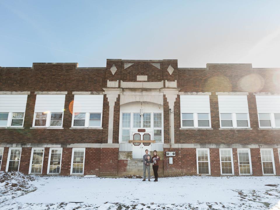 The couple and their children stand in front of the Indiana schoolhouse.