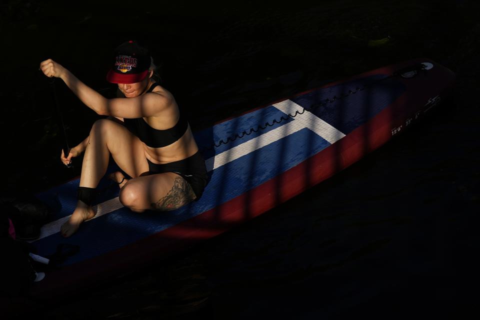 A woman paddles on a SUP-board in Moskva river at Serebryany Bor park in Moscow, Russia, Thursday, July 11, 2024. Warm weather has settled in Moscow with a temperature of 30 Celsius, (86 Fahrenheit) and will increase in the coming days. (AP Photo/Pavel Bednyakov)