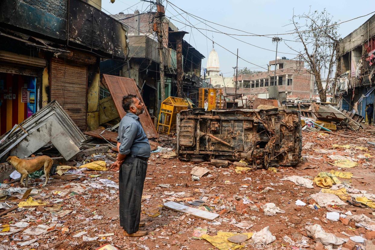 A resident stands by burned-out and damaged homes and shops following clashes in Delhi on Wednesday: AFP/Getty