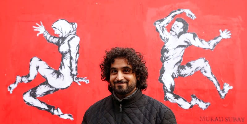 Yemen's street artist Murad Subay poses after unveiling a street painting to denounce the conflict in his country, in Paris