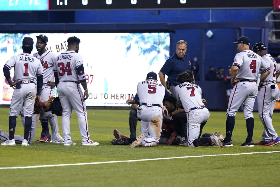 Atlanta Braves gather around right fielder Ronald Acuna Jr., lying on his back, after he attempted to walk after trying to make a catch on an inside-the-park home run hit by Miami Marlins' Jazz Chisholm Jr. during the fifth inning of a baseball game Saturday, July 10, 2021, in Miami. (AP Photo/Lynne Sladky)